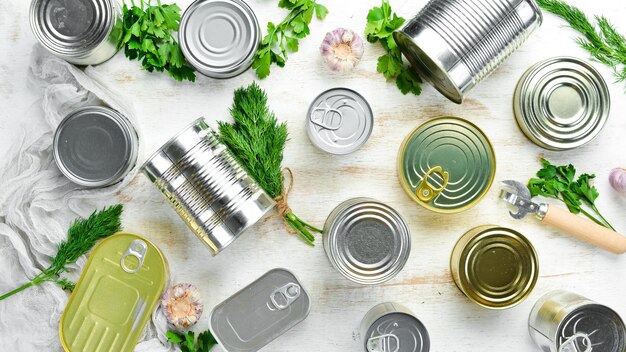 Canned food in tin jars on white wooden background Top view