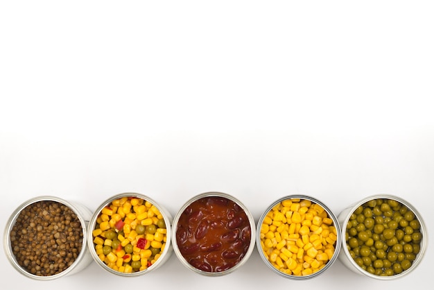 Canned food on white background. Green pea, beans, corn, lentils.