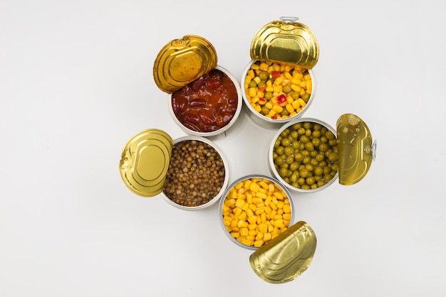 Canned food on white background Green pea beans corn lentils