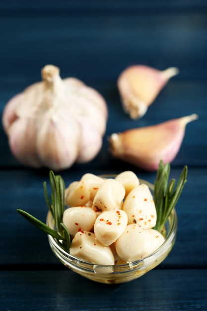 Canned garlic in glass bowl on color wooden background