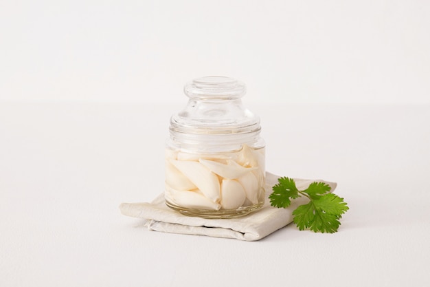 Canned garlic in a glass jar on top of a towel