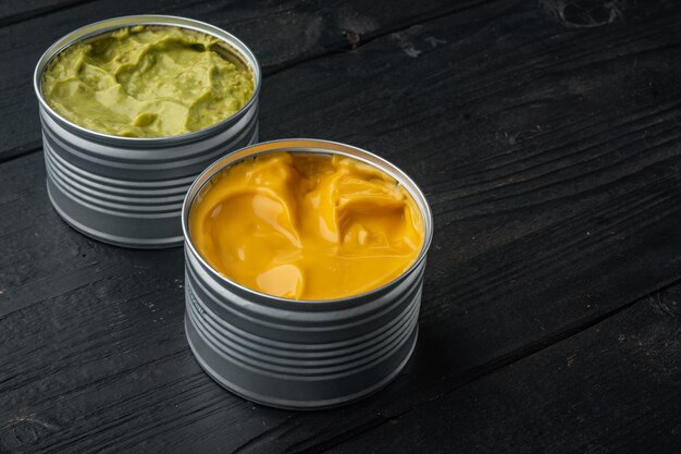 Canned guacamole and cheese dip in can, on black wooden background