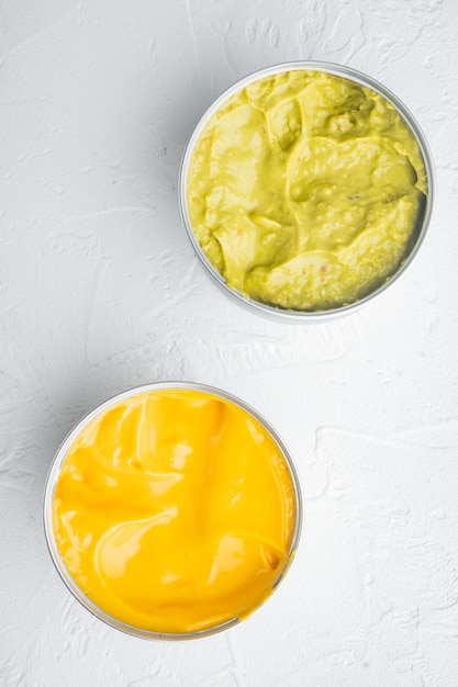 Canned guacamole and cheese dip in can, on white table, top\
view or flat lay