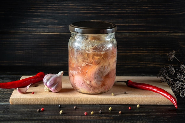 Canned meat or stew in a glass jar with spices on a wooden board Farm organic products