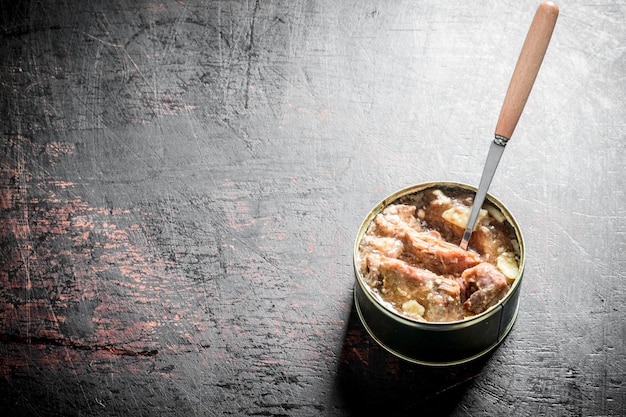 Canned meat in a tin with a spoon