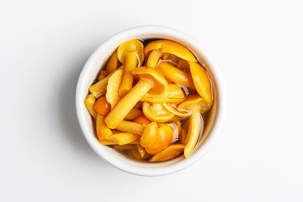 Canned mushrooms in a bowl on a white background. Top view.
