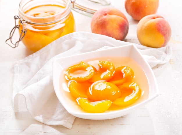 Canned peaches in a bowl on wooden table