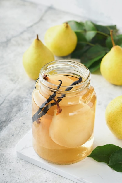 Canned pear compote with vanillin Pear compote Homemade delicious canned pear compote in glass jars at home on a light background Homemade food Space for text