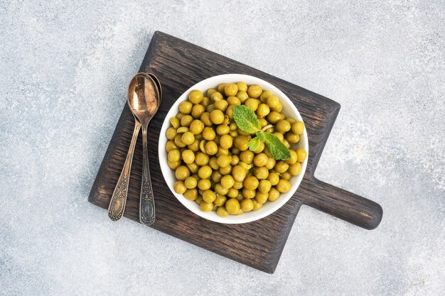 Canned peas in a plate on a wooden Board