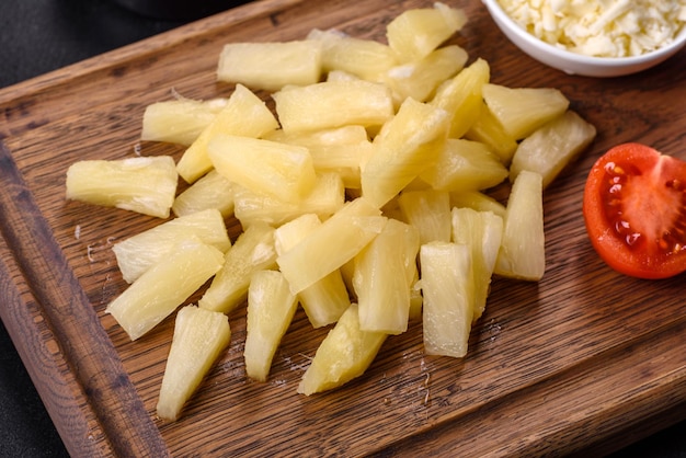 Canned pineapple chunks in a white bowl on a dark concrete background