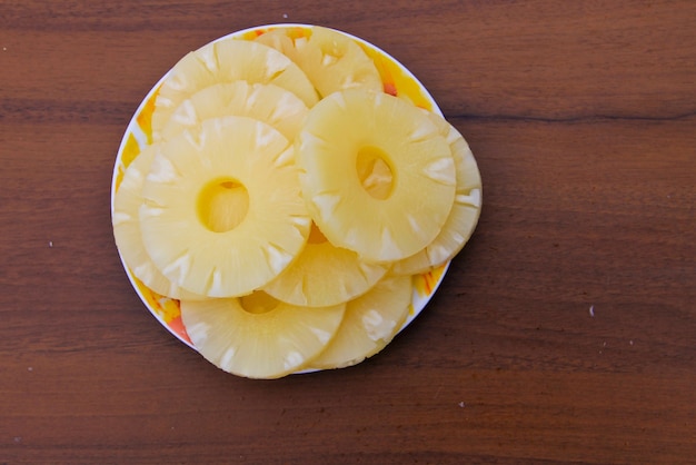 Canned pineapple on a plate on the wooden table