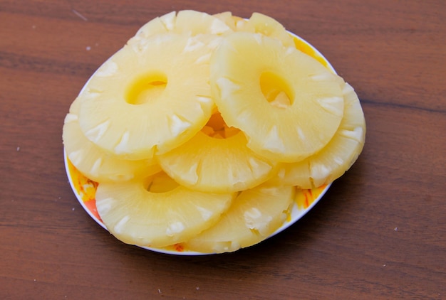木製のテーブルの上の皿に缶詰のパイナップル