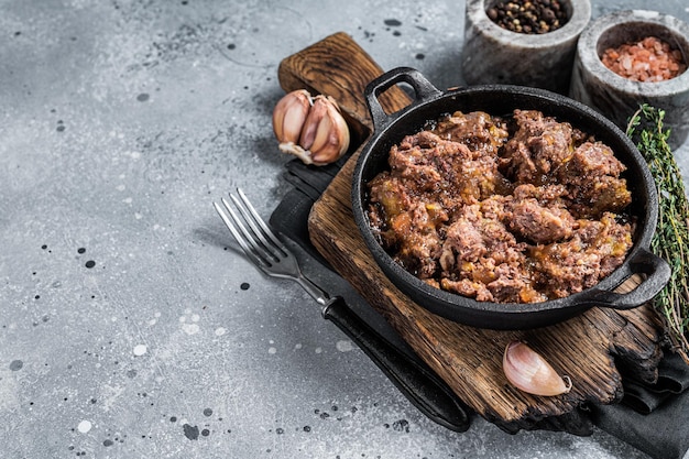 Canned stewed horse and beef meat in a pan. Gray background. Top view. Copy space.