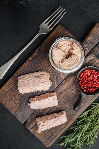 Canned tuna fillet meat in olive oil on black background top view