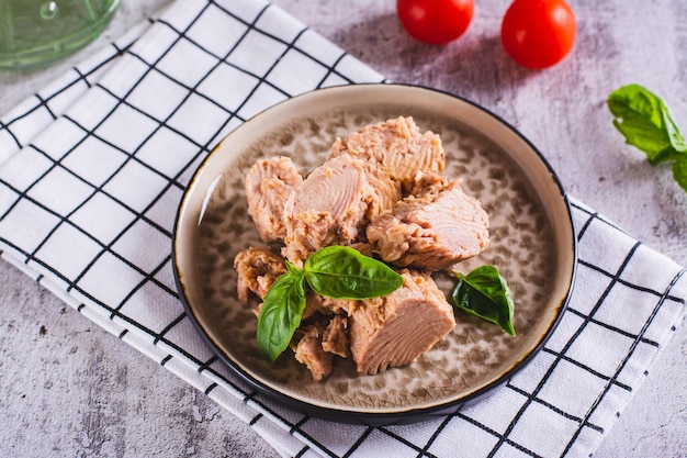 Canned tuna fish meat and basil on a plate on the table