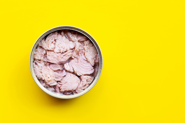 Canned tuna fish on yellow table