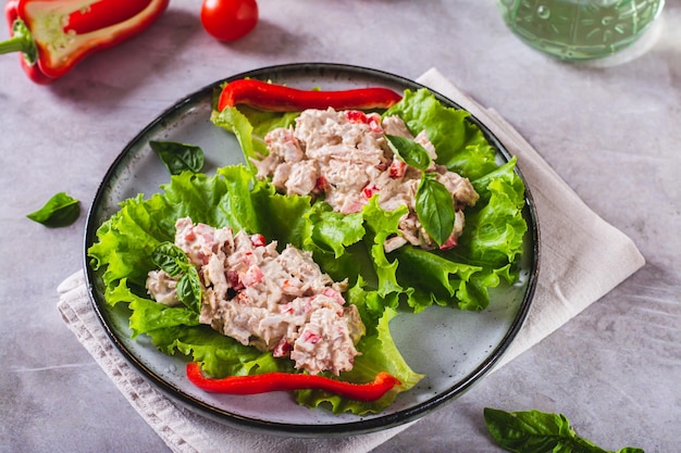 Foto insalata di tonno in scatola con pepe e uovo su foglie di lattuga su un piatto