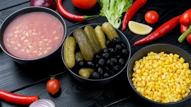 Canned vegetables in a plate. cucumber, corn, beans. On a black board
