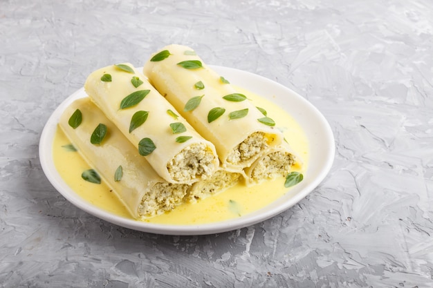 회색 콘크리트에 계란 소스와 함께 Cannelloni 파스타