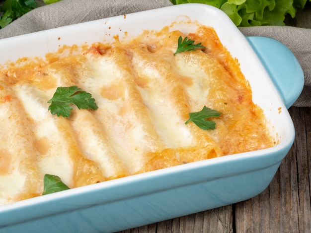 Cannelloni with filling of ground beef, tomatoes, baked with bechamel tomato sauce