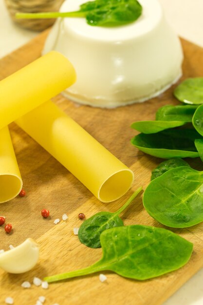 Cannelloni with ricotta and spinach on wooden table. Traditional Italian food ingredients.Italian cuisine