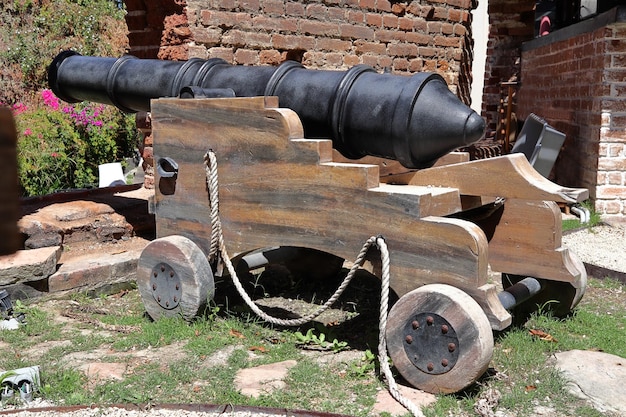 A cannon is on display in front of a brick building