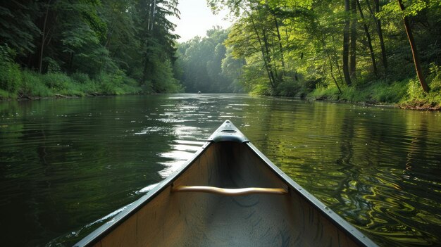 Canoe-avontuur in een serene bosrivier De boeg van een kano snijdt door het rustige water van een rivier omringd door het weelderige groen van een dicht bos dat een gevoel van vrede en avontuur oproept
