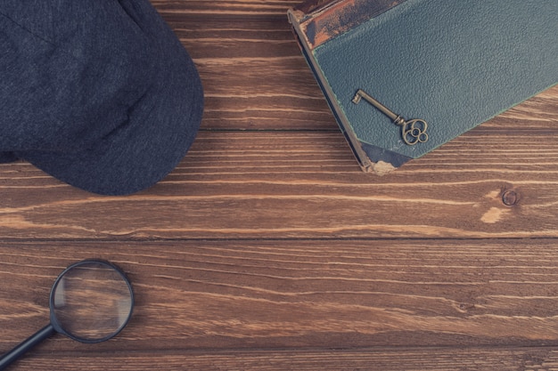 Cap of a detective, a magnifying glass and an old book