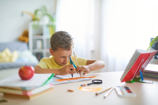 Capable boy, enthusiastically drawing a geometric shape with a compass, circle.