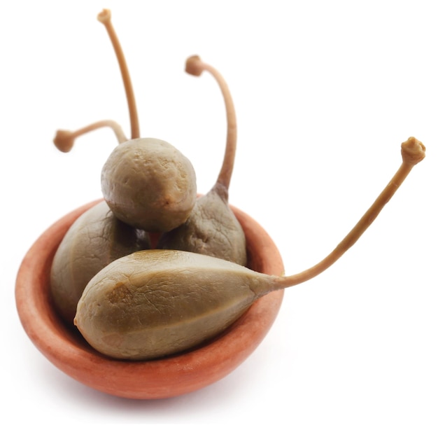 Caper berry in a bowl over white background