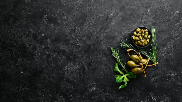Capers Marinated capers in a bowl on a black stone background Top view Free space for your text
