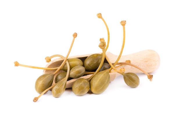 Capers in a wooden spoon, isolated on white