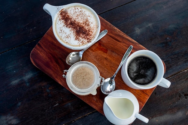 木製のテーブルにミルクとカプチーノとアメリカーノコーヒー