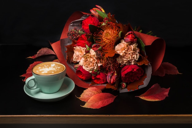 写真 カプチーノと美しい花の花束の静物画。フラワーショップの構成。コーヒーカップ