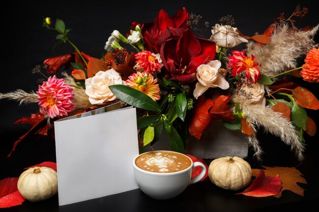 Photo cappuccino and beautiful flowers still life. flower shop composition. coffee cup, apple, fresh and bouquet on black wooden table. florist art and floral design concept