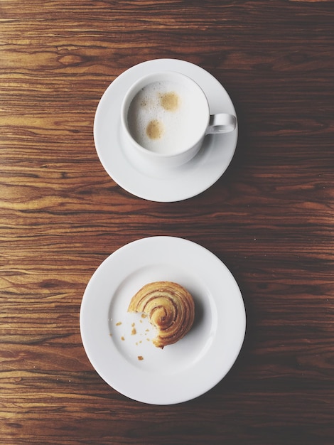 Foto cappuccino e brioche su un tavolo.