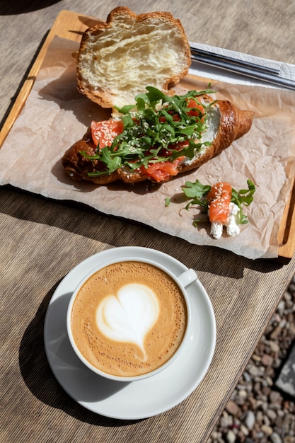 Photo cappuccino and bun breakfast at the cafe. american morning. croissant with trout and arugula
