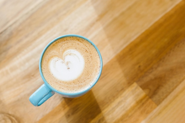 カフェの木製テーブルに青いカップのカプチーノコーヒー上面図