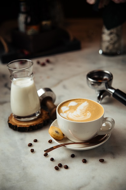 Cappuccino coffee for breakfast with milk and cookies on a white marble table