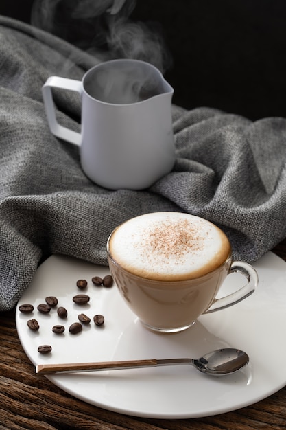 カフェのコーヒーショップメニューの木の背景にカプチーノのコーヒークリアカップ