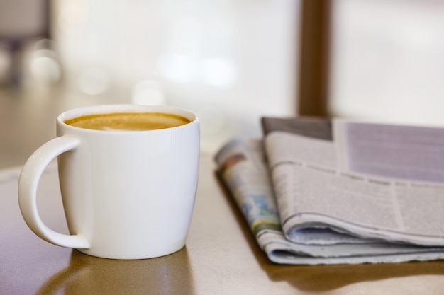 Cappuccino coffee cup on wooden table with newspaper