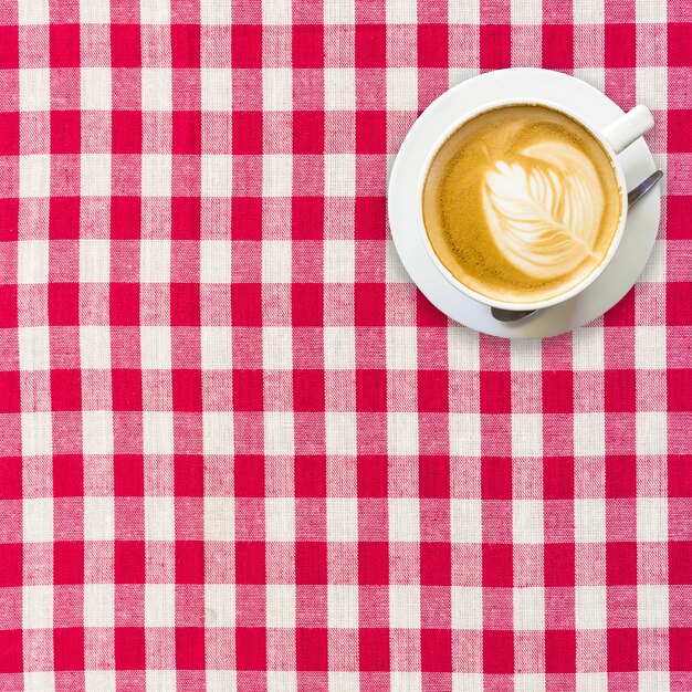 Foto caffè del cappuccino sulla fine a quadretti bianca e rossa della priorità bassa su