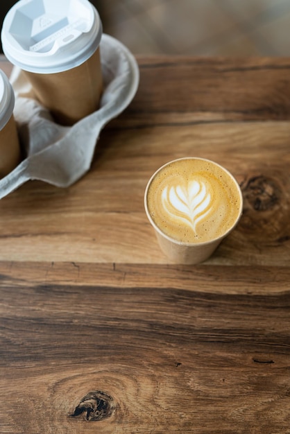 Cappuccino coffee with beautiful pattern on foam in eco craft glass on table favorite coffee cup concept. Coffee to go concept.