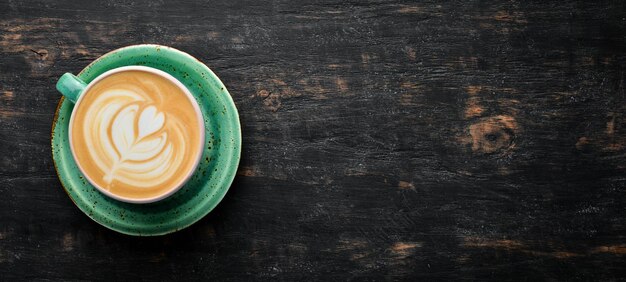 Cappuccino caffè con latte su fondo di legno nero vista dall'alto spazio per la copia gratuito