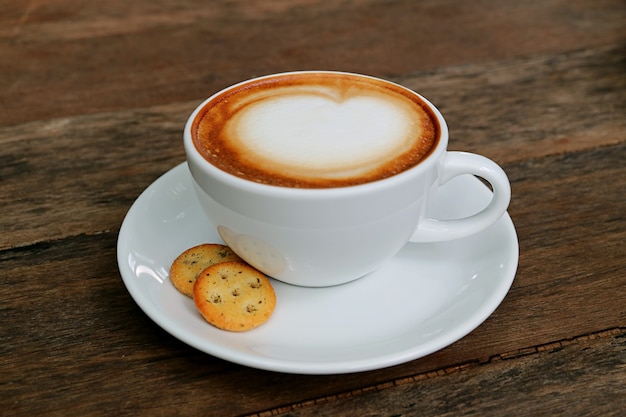 Cappuccino coffee with a pair of crackers isolated on wooden table