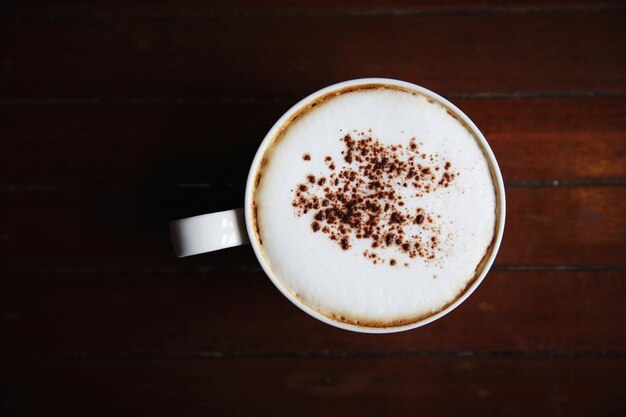 コーヒーショップで木の背景にカプチーノコーヒー