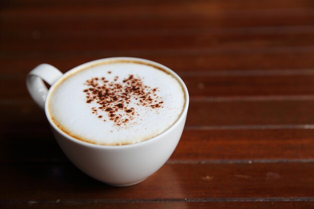 Cappuccino coffee on wood background in coffee shop