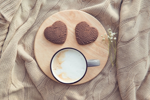 カプチーノカップとハート型のチョコレートクッキー、バレンタインのベッドでの朝食