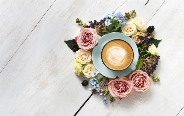 Composizione nei fiori e nel cappuccino. tazza da caffè blu con schiuma cremosa, fiori freschi e secchi