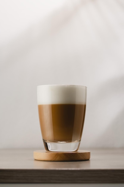 Photo cappuccino in a glass cup on a wooden table coffee and froth milk